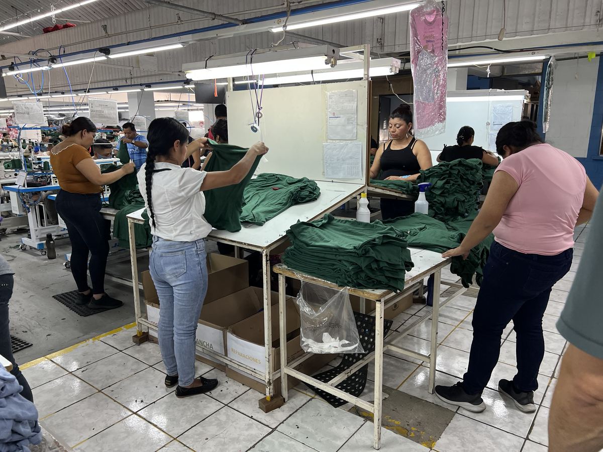 Workers inspecting and folding garments at the end of a sewing line